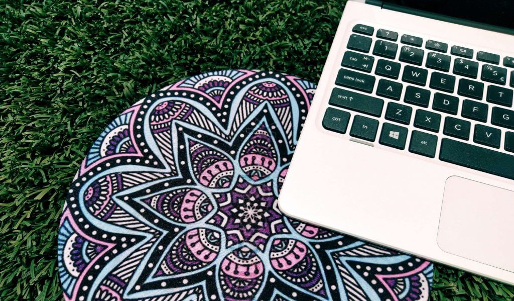 a yoga mat lying under a laptop on grass