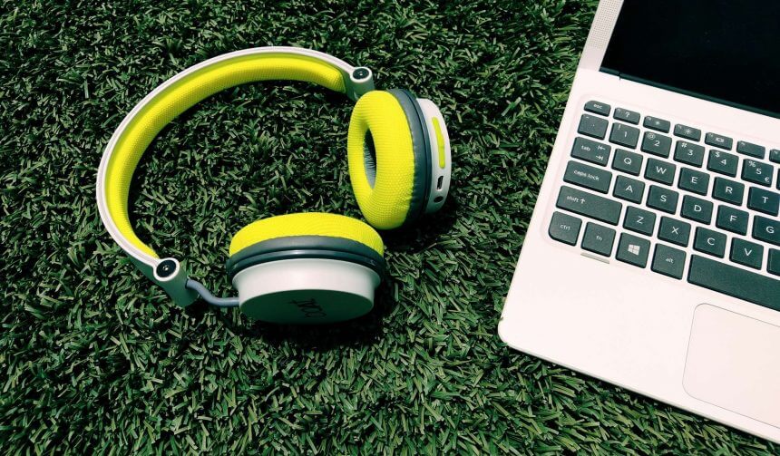 a pair of headphones laying next to a laptop on gras