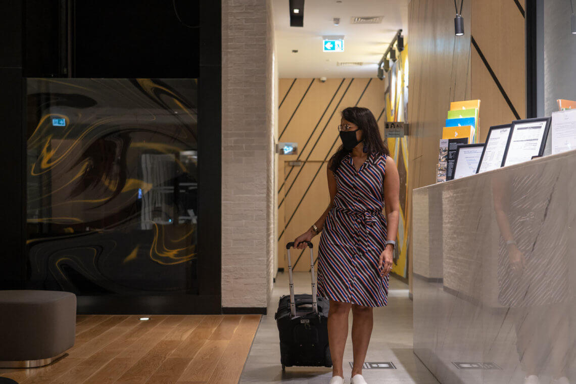 woman walking in a hotel lobby with a trolley bag