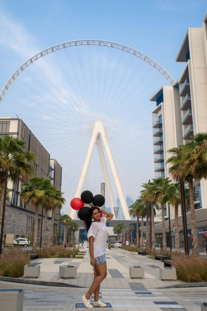 girl posing in front of dubai eye with balloons