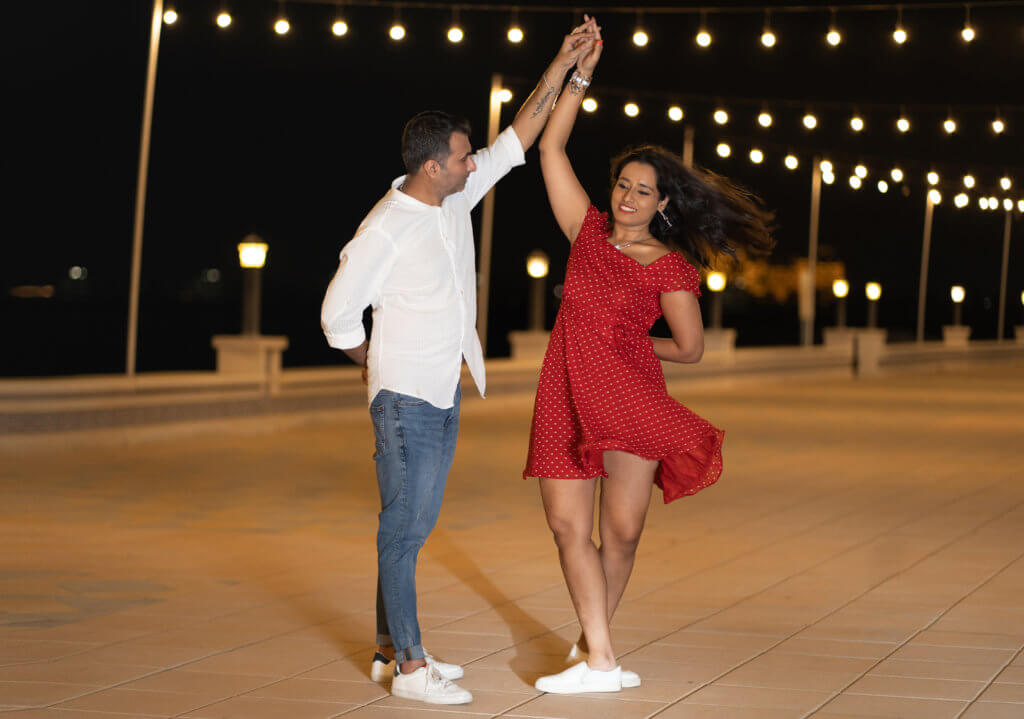 a couple dancing in the evening with fairy lights in the background